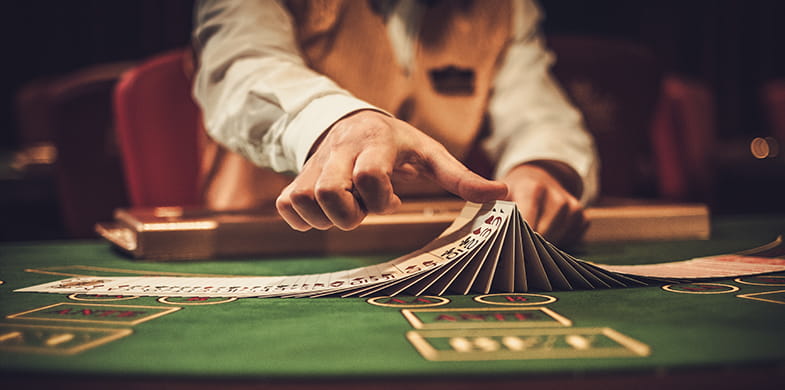 Unas manos de crupier que barajan las cartas en una mesa de casino