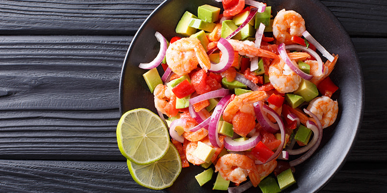 Plato de ceviche peruano realizado con pescado o marisco marinado en cítricos y cilantro en primer plano. 